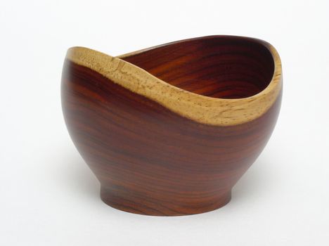 An empty bowl made of Costa Rican rosewood, standing on a plain white backdrop. The bowl is a mid reddish-brown, with light tan edging.