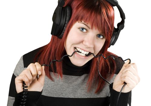 Cute girl with red hair biting the cord of her headphones while listening to music.

Studio shot.