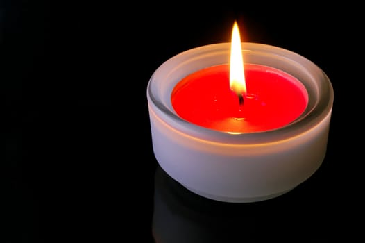 Red (isolated)  lighted candle in black background 