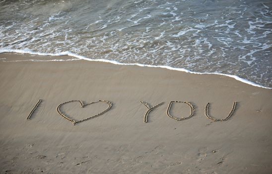 Words about love written on wet sand