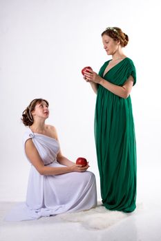 Two ladies in antique dress and two apples on white background
