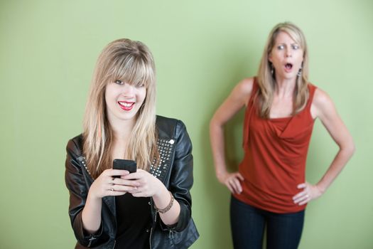 Upset mom with happy teen on mobile phone