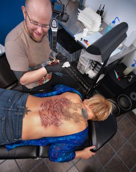 Smiling tattoo artist with client in studio