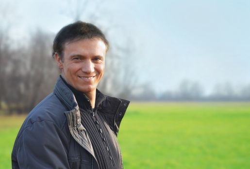 Handsome young man smiling in a green field