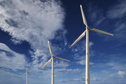 Wind turbines against a blue sky with clouds