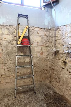 Red helmet and wooden step ladder on work place