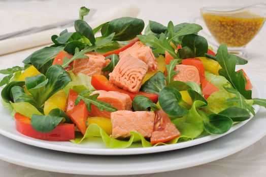 Vegetable salad with slices of salmon, roots, arugula, tomatoes and peppers, seasoned with mustard sauce with curry