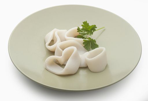 Some raw rings of squid with parsley on the plate