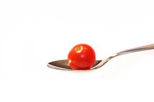 A cherry tomato on a spoon. All isolated on white background.