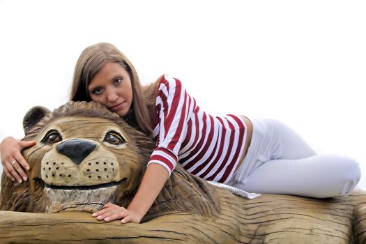 A young handsome woman posing on a wooden lion. All isolated on white background.