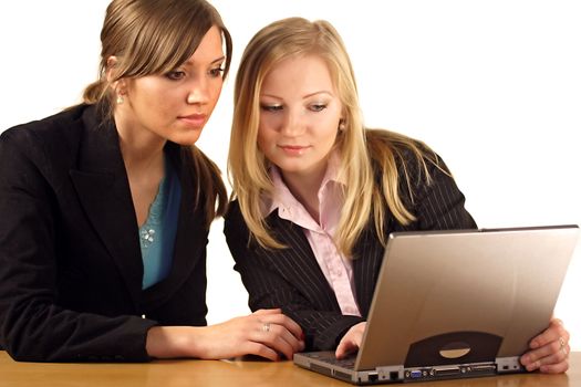 Two aspiring businesswomen working on a notebook computer. All isolated on white background.