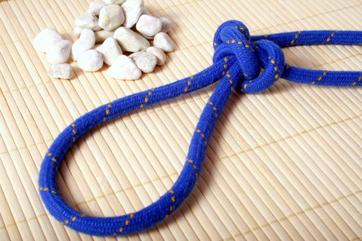 A fine knotted bowline knot lying next to a pile of rocks.