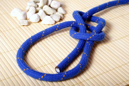 A fine knotted bowline knot lying next to a pile of rocks.