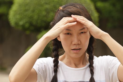 Asian women are holding head with hands because of headaches