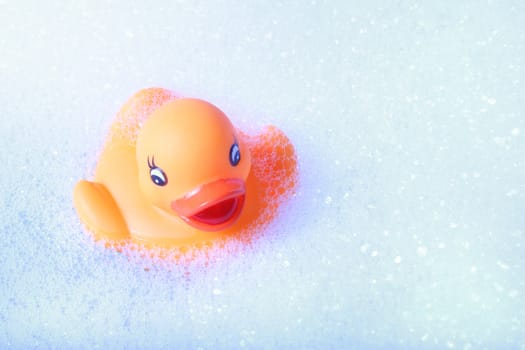 A rubber duck swimming in a foam bath.