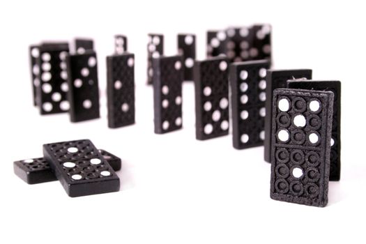 Several dominoes standing one after another in front o a white background.