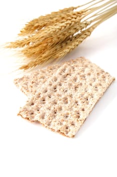 Some crispbread next to wheat. All isolated on white background.