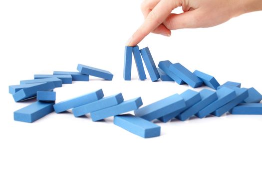 A human hand intervenes a chain reaction of a domino game. All isolated on white background.