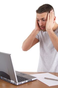 A frustrated young man in front of his notebook computer. All isolated on white background.
