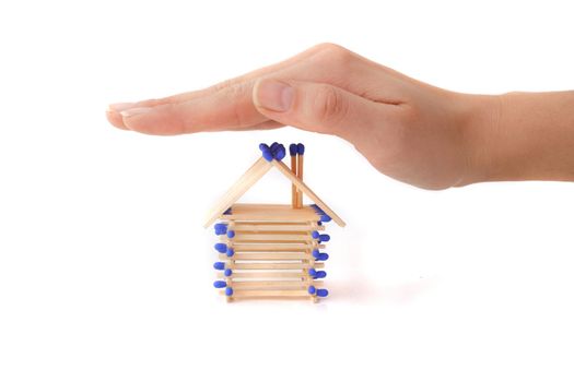 A human hand protecting a stylized house out of matchsticks. All isolated on white background.