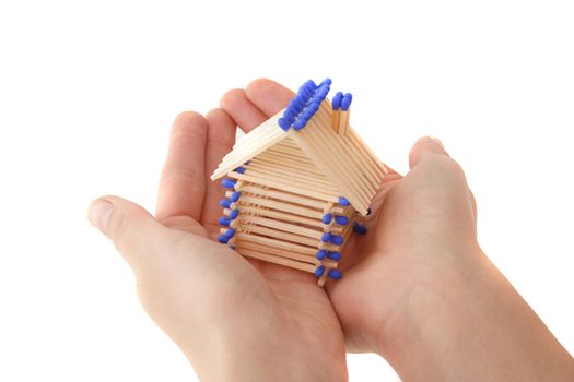 A human hand protecting a stylized house out of matchsticks. All isolated on white background.