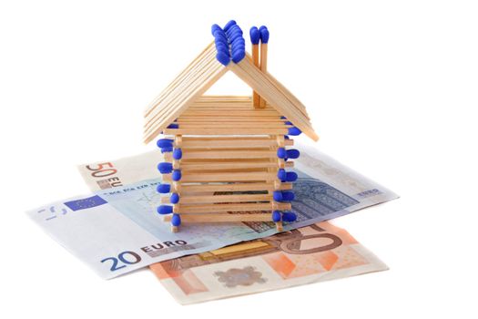 A stylized house out of wood standing on two bank notes. All isolated on white background.