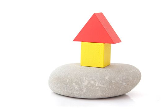 A stylized house out of colorful blocks on a natural stone. All isolated on white background.