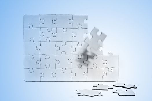 A jigsaw puzzle with various missing pieces. All in front of light blue background.