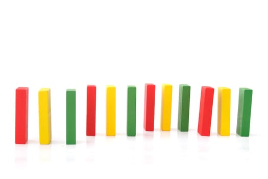 Several multicolored dominoes standing one after another. All isolatoed on white background.