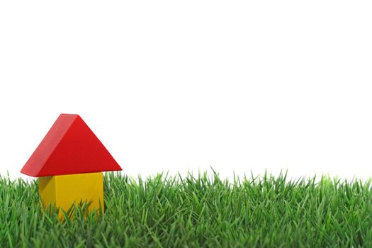 A stylized house out of blocks between blades of grass. All isolated on white background.