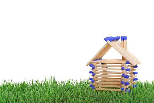 A stylized house out of blocks between blades of grass. All isolated on white background.