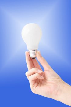 Human hands holding a  bulb in front of a bright blue sky.