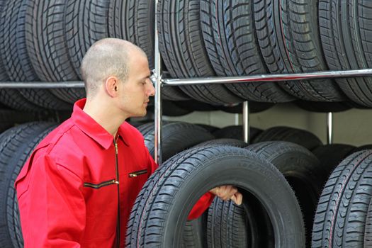 A working mechanic in a garage putting tires in a rack.