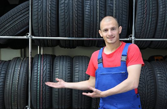 A smiling mechanic in a garage presenting the range of goods.
