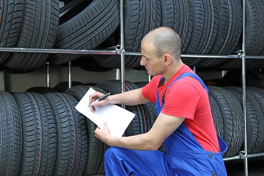 A worker takes inventory in a tire workshop and checks the stock.