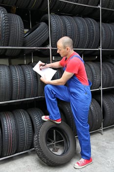 A worker takes inventory in a tire workshop and checks the stock.