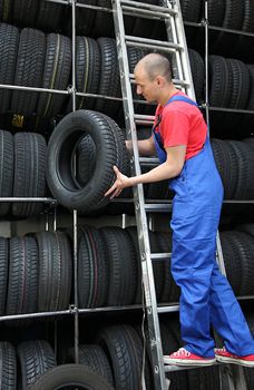 A motivated worker in a tire workshop restocking the goods.
