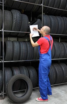 A worker takes inventory in a tire workshop and checks the stock.