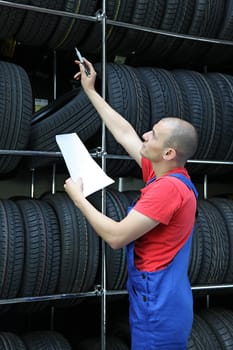 A worker takes inventory in a tire workshop and checks the stock.