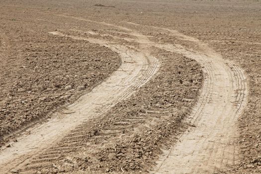 Tire tracks leading on a wide open fallow land.