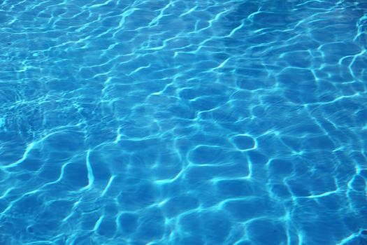 The surface of a shiny blue swimming pool.