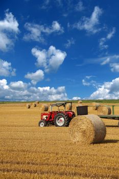 A wide open field showing some bales of straw.