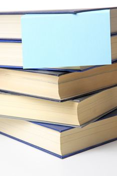 Several books lying one upon another. A notepad is attached. All on white background.