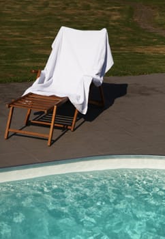 Showing a deck chair next to a swimming pool.