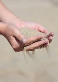 A person holding dry sand in his hands.