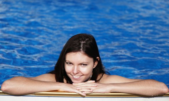 A very attractive young woman refreshing in a swimming pool.