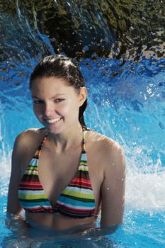 A very attractive young woman refreshing in a swimming pool.