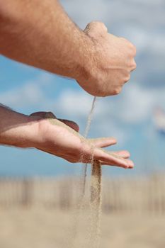 A person holding dry sand in his hands.