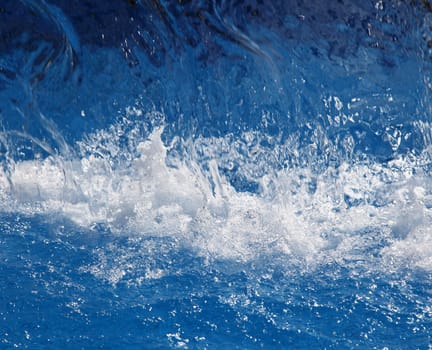 Splashing shiny blue water in a swimming pool.