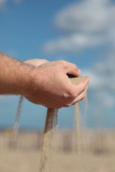 A person holding dry sand in his hands.